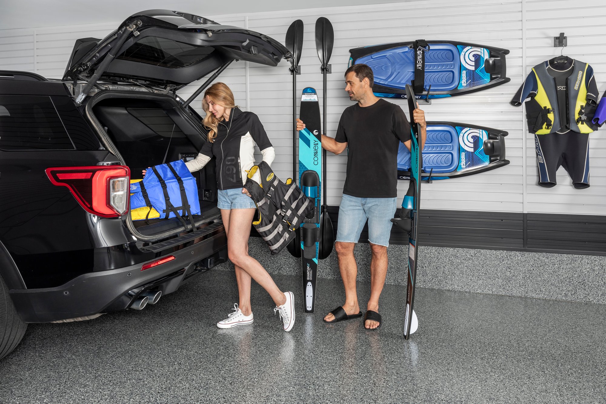A man and woman are organizing water sports gear in a sleek garage by Garage Living