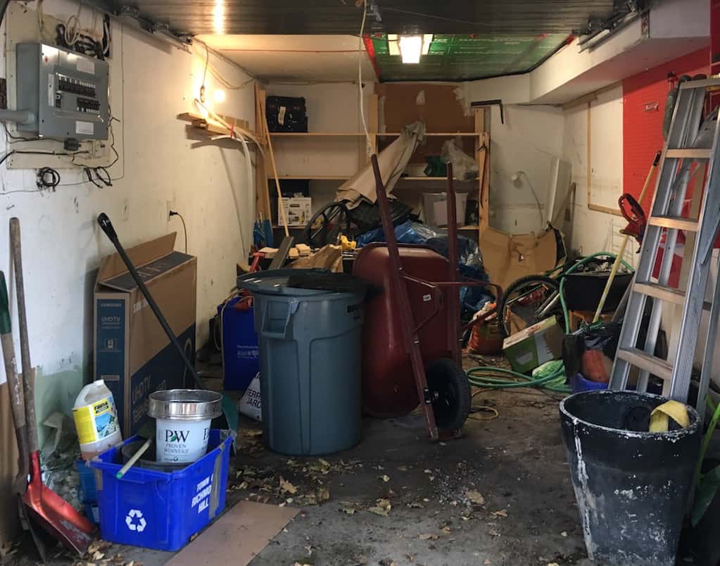 Messy single car garage with clutter and junk.