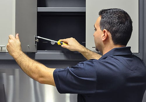 man with screwdrivers installing cabinetry garage makeover process installation