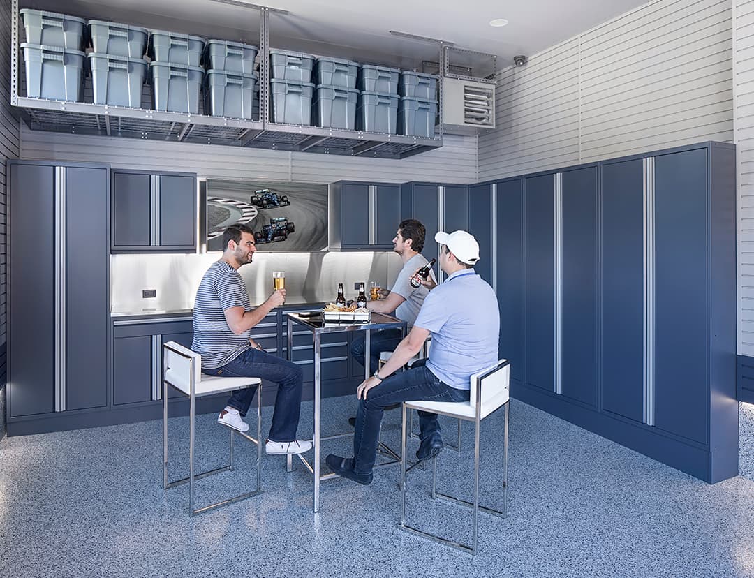 3 men watching F1 race in garage socializing