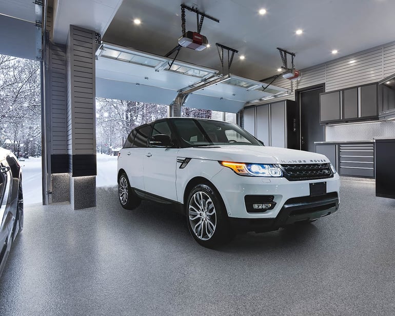 New garage floor with white Range Rover driving into garage on snowy day.