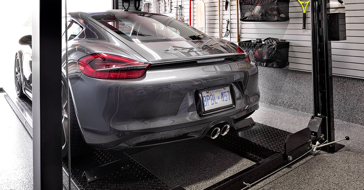 Grey Porsche on a four post car lift.