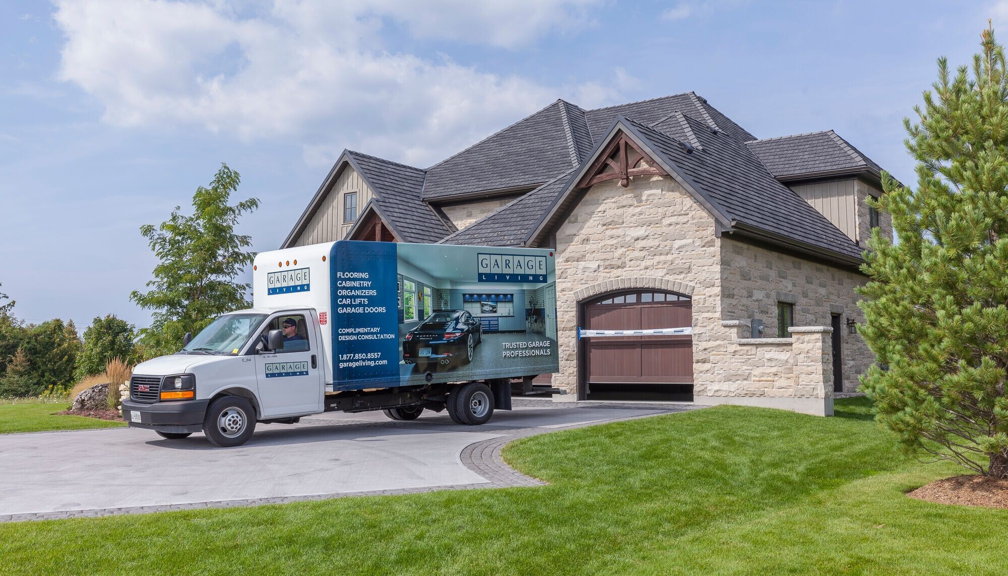 The Garage Living work truck is shown in the driveway of a mansion with a brand new garage installed