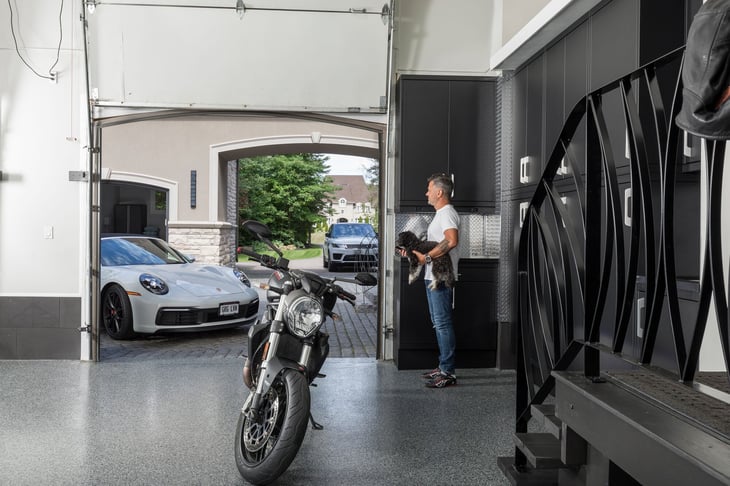 Homeowner standing with his dog in a fully designed garage, reflecting pride in a thoughtfully crafted space
