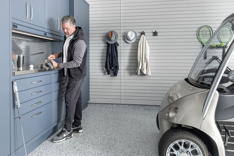Luxury garage design with golf storage, custom cabinetry, slatwall organization, and a parked golf cart
