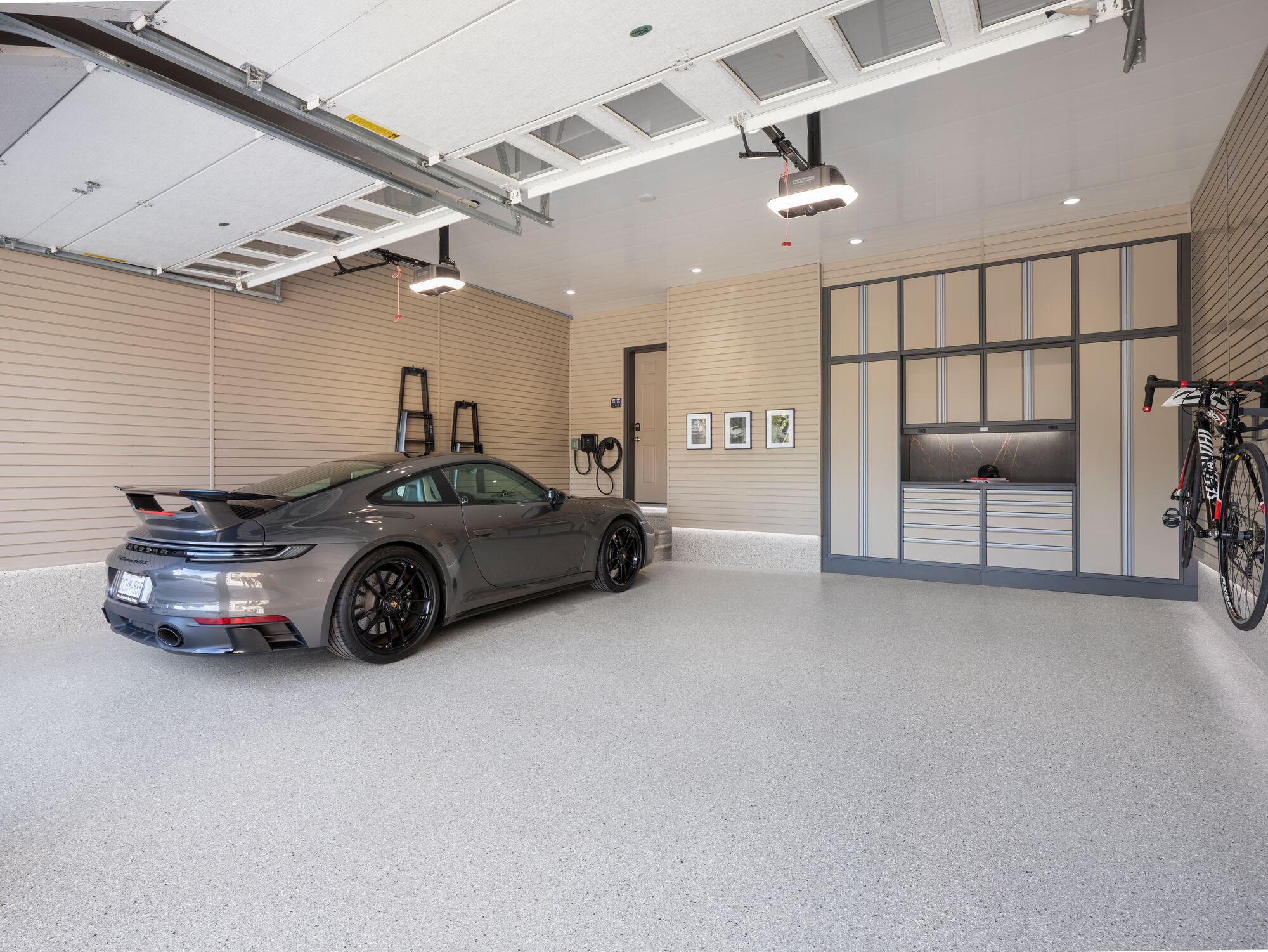 Detailed view of a custom garage featuring built-in cabinets, slatwall storage, work area, and a Porsche 911