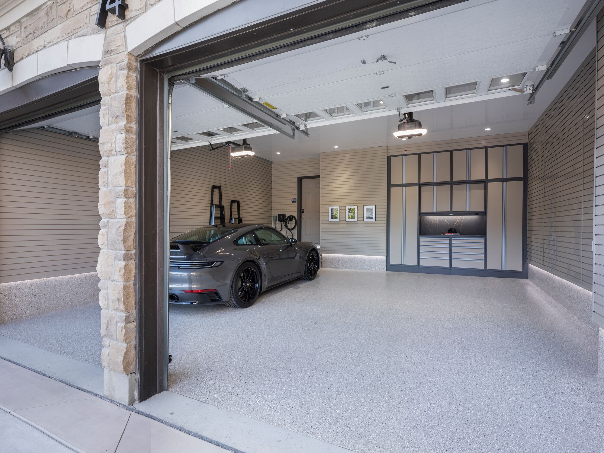 Wide view of a finished garage with a Porsche 911, custom cabinetry, and seamless floor coating